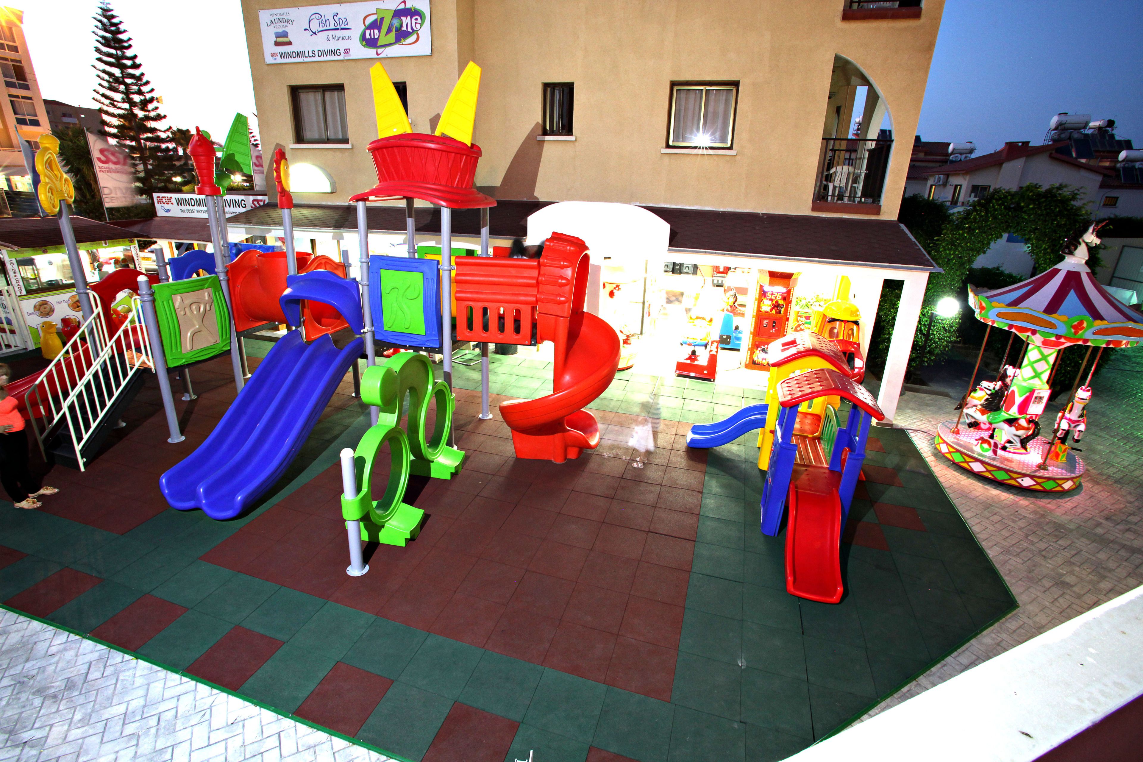 A playground with slides and climbing structures in front of a building with a sign for windmills diving.