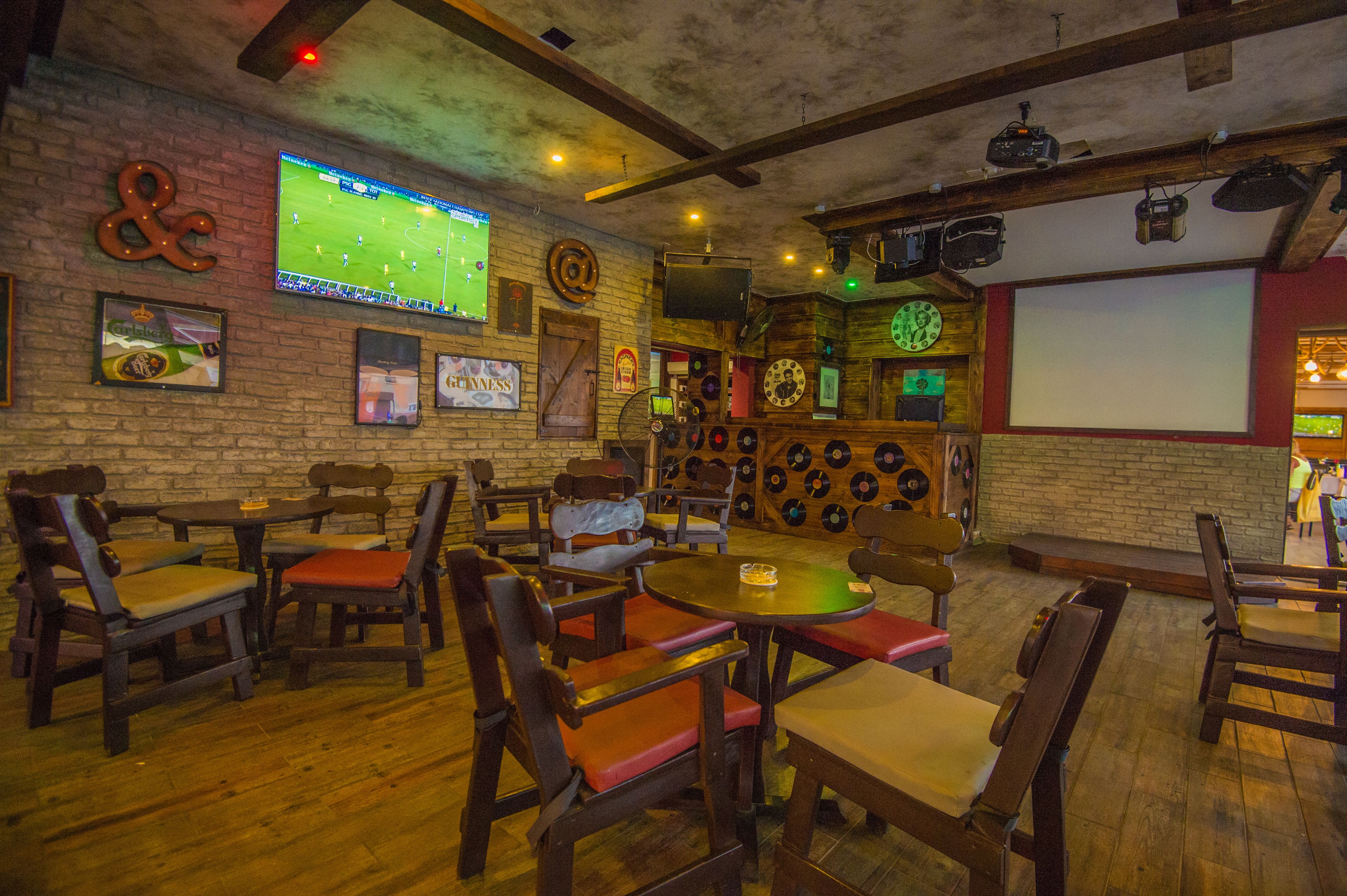 A bar with wooden furniture, a large screen, and a wall decorated with records and a Guinness sign.