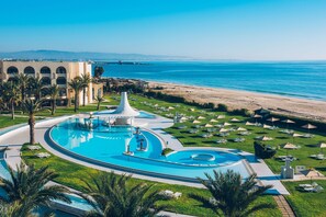 Un complexe hôtelier doté d’une grande piscine, d’une plage et de palmiers.