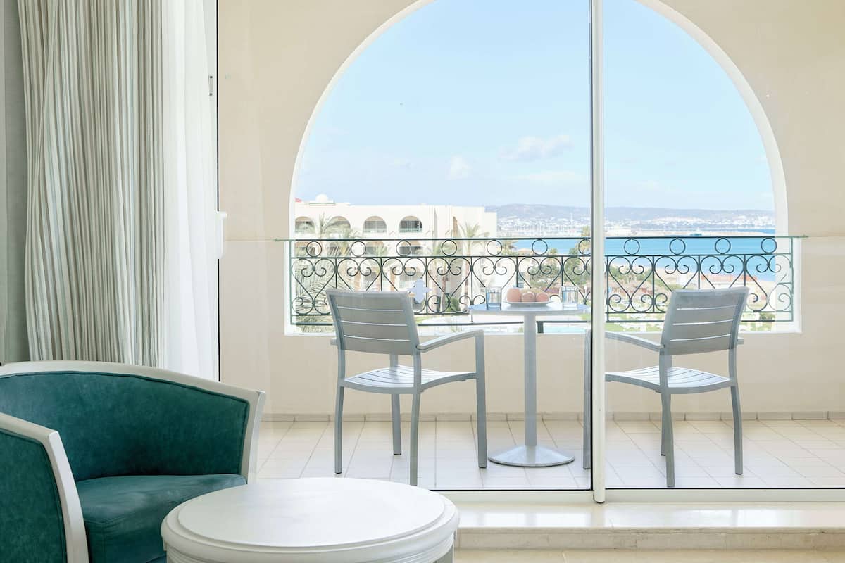 Een balkon met uitzicht op een stad en zee, een tafel, twee stoelen en een bank.