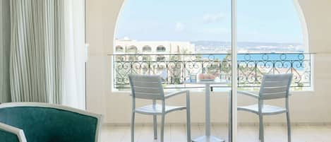 Un balcon avec vue sur la ville et la mer, une table, deux chaises et un canapé.