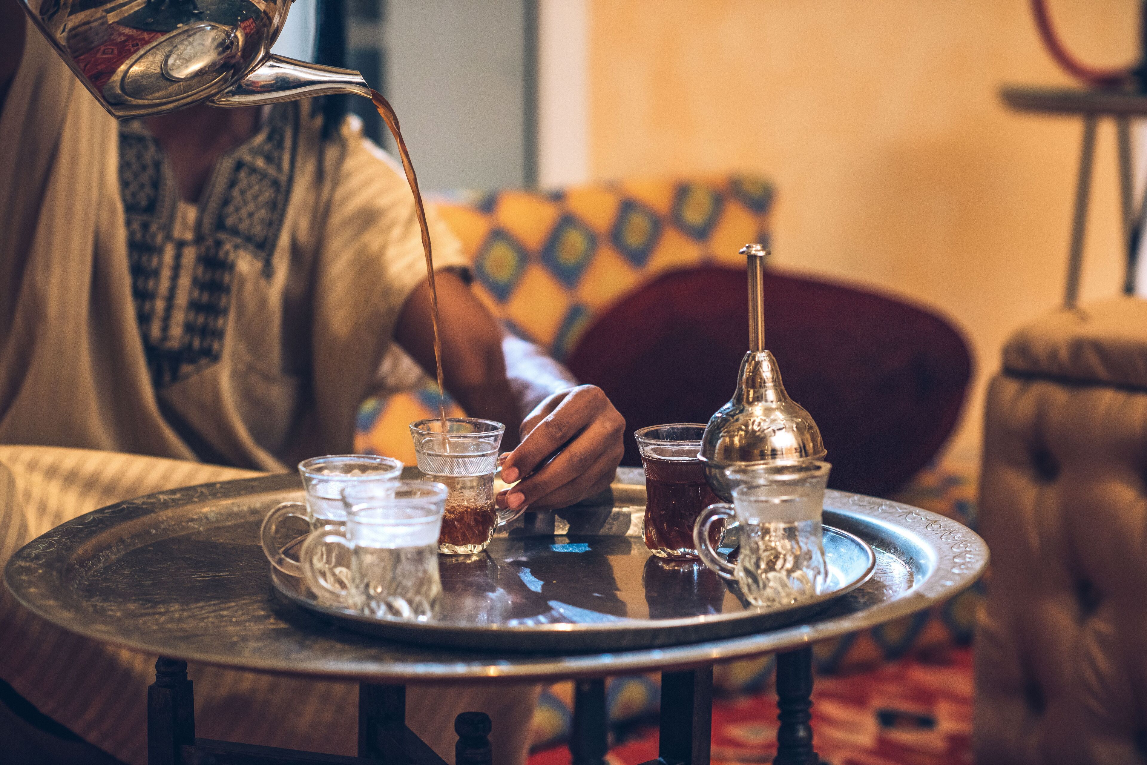 A tray with several glasses and a teapot on a round table.