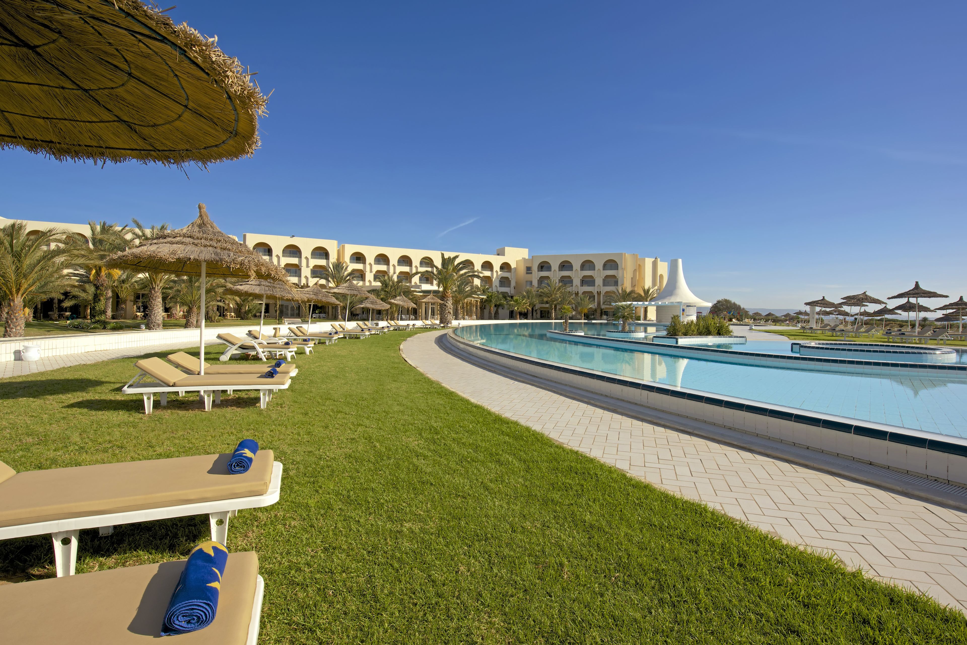 A poolside area with lounge chairs, umbrellas, and a large pool.