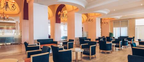 A spacious lobby with multiple seating areas, a reception desk, and decorative chandeliers.