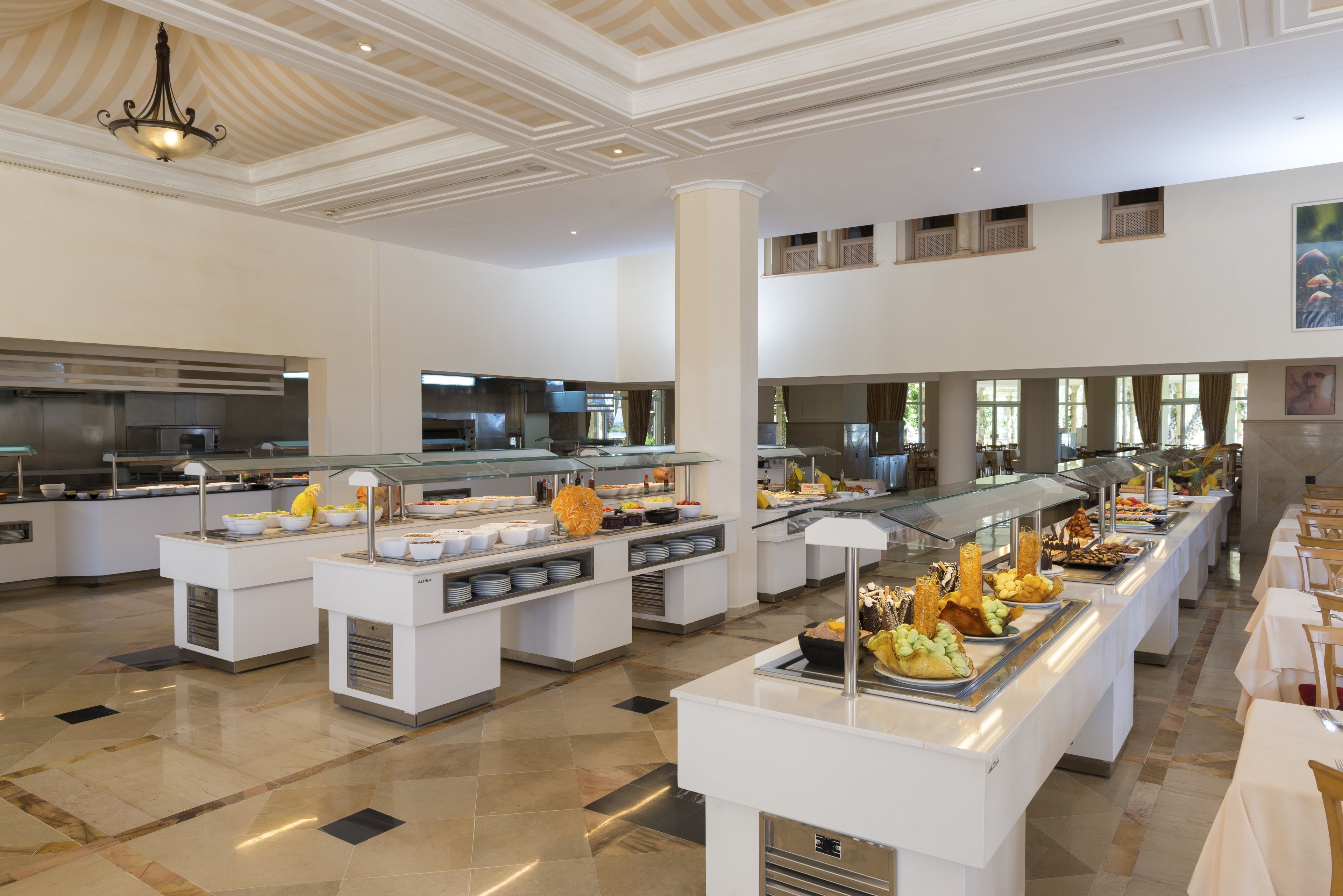 A spacious buffet area with multiple serving stations, a high ceiling with decorative molding, and a clean, modern design.