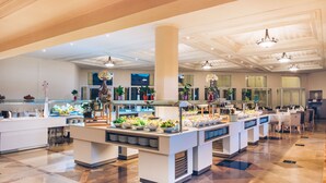 Un espace buffet comprenant plusieurs présentoirs de nourriture, un pilier central et un sol carrelé.