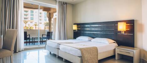 A hotel room with a large bed, two bedside tables, a chair, and a view of the outside balcony.