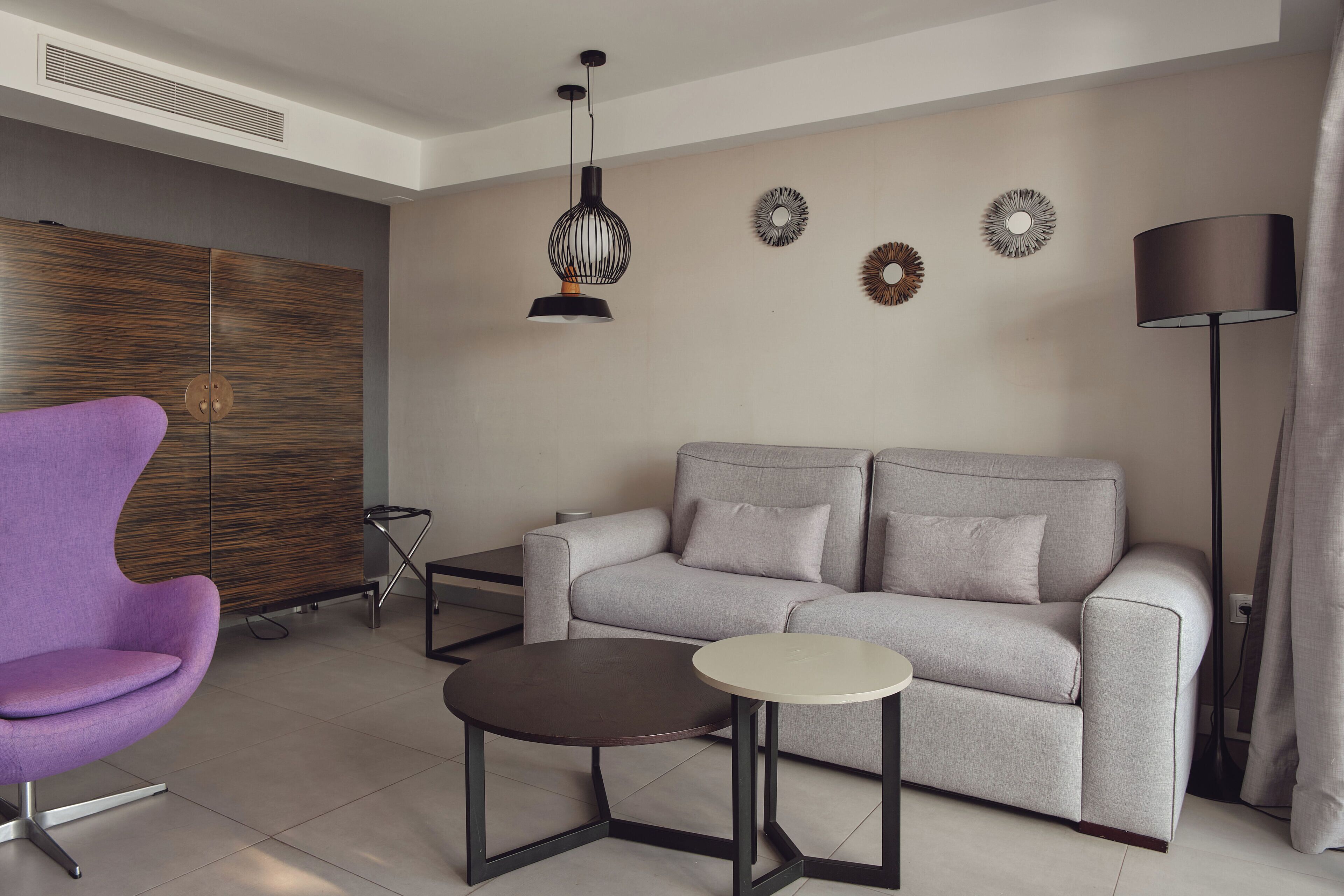 A modern living room with a grey sofa, a purple armchair, a small round table, and a floor lamp.