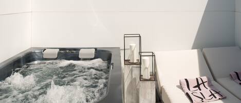 Un área de spa con un jacuzzi y un sofá blanco con una toalla.