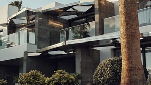 A modern multi-story building with a concrete facade, large windows, and a palm tree in the foreground. - La Isla y el Mar Hotel Boutique - Adults Only (Tías)