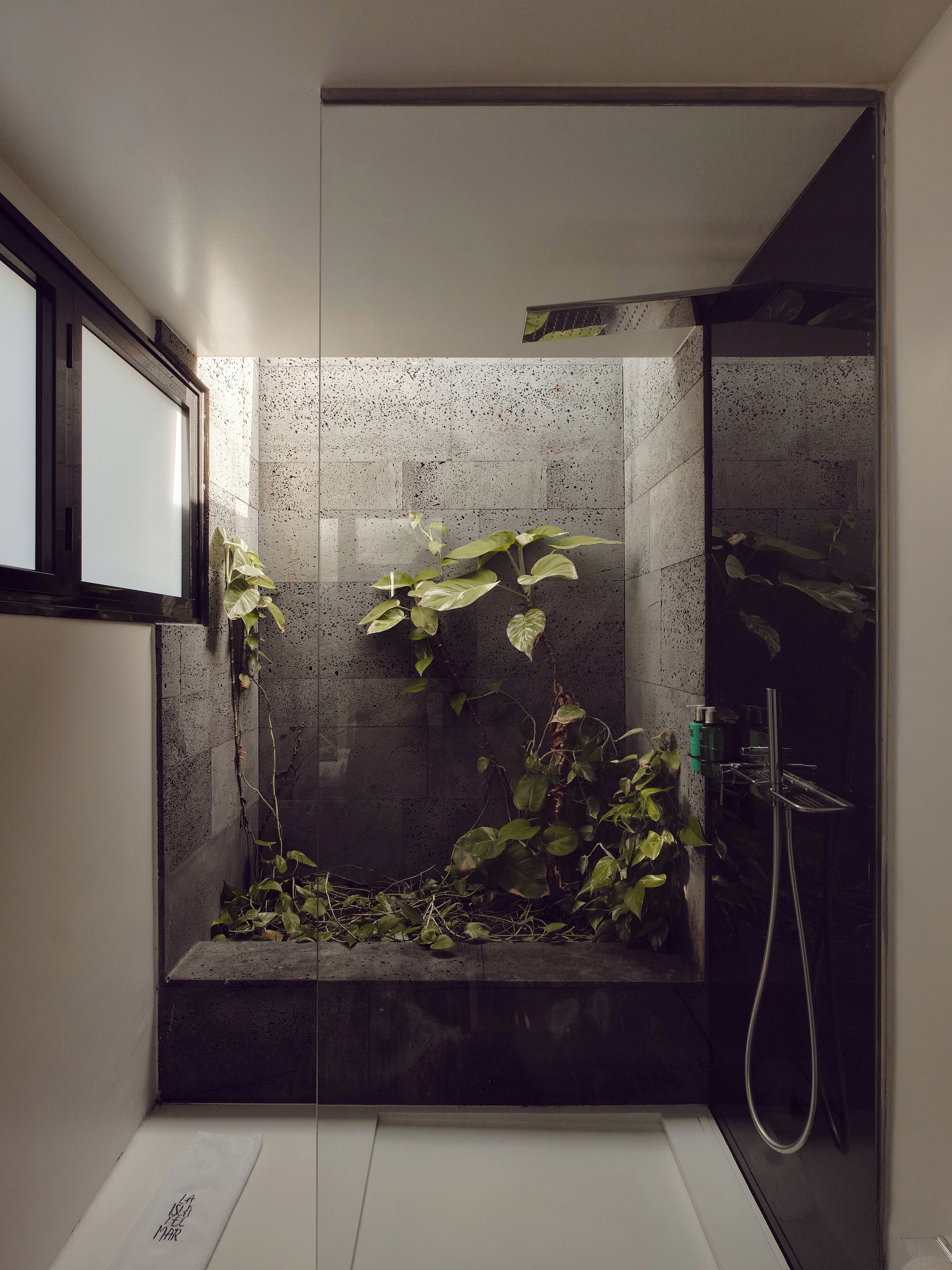 Eine moderne Dusche mit Glasabtrennung, einer kleinen Sitzbank und einer Handbrause.
