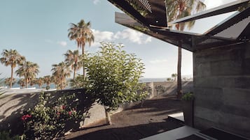 Un espacio exterior moderno con un muro de piedra, un banco y un árbol con flores rosadas.