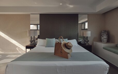 A hotel room with a large bed, a nightstand with a lamp, a decorative vase, and a suitcase on the bed.