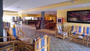 A lobby with striped armchairs, a coffee table, and a large painting on the wall. - Caleta Garden (Antigua)