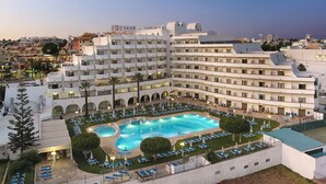 A large hotel with multiple balconies, a swimming pool, and outdoor seating areas. - Hotel Apartamento Brisa Sol (Albufeira)