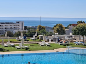Relax by the pool with a view of the sea, surrounded by comfortable lounge chairs and umbrellas.