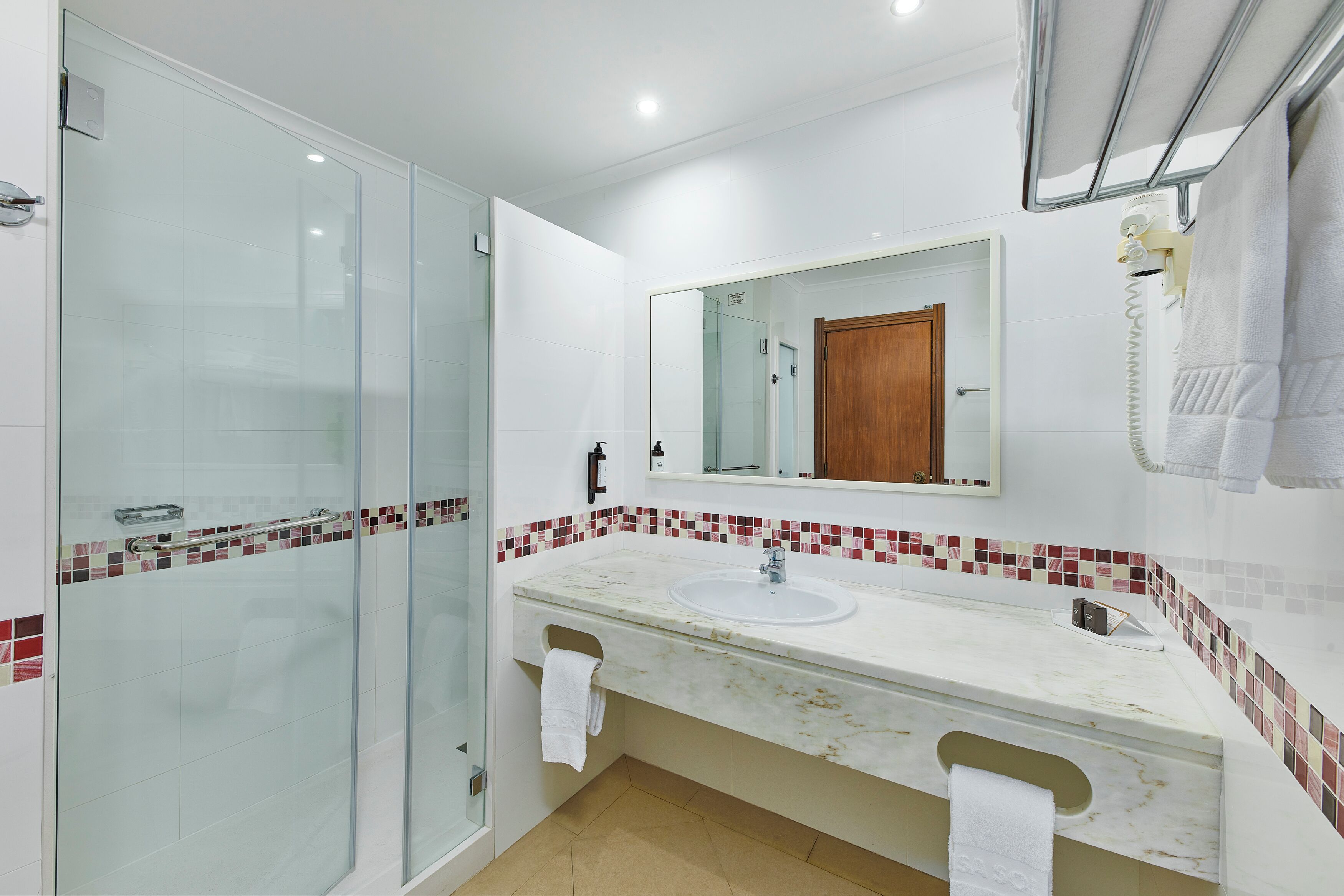A modern bathroom with a glass shower enclosure, a marble sink, and a tiled backsplash.