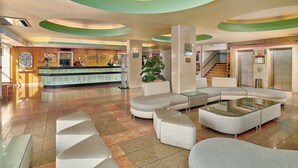 A spacious lobby with a reception desk, seating area, and a staircase leading to an elevator. - Hotel Apartamento Brisa Sol (Albufeira)