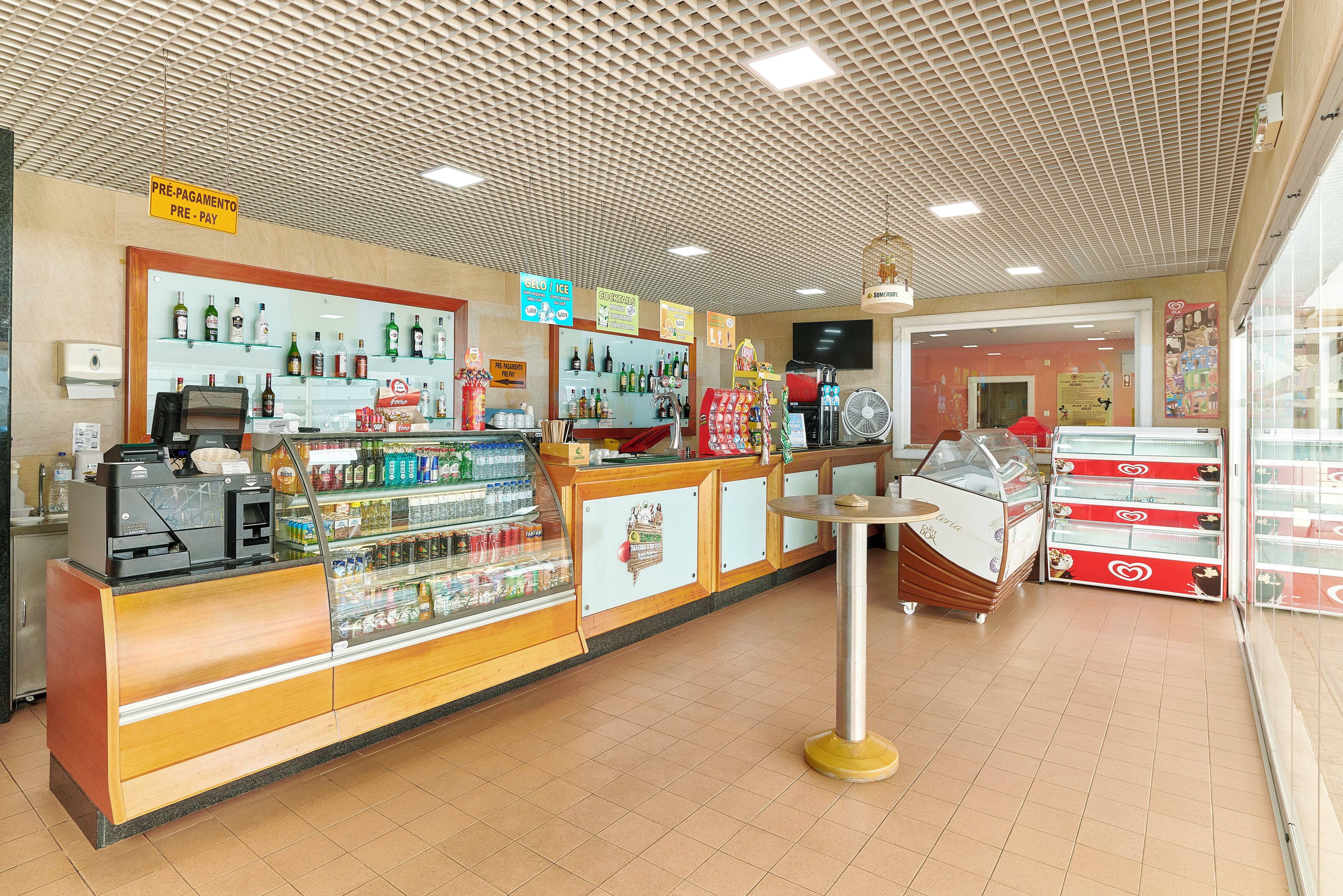 A bakery counter with a cash register, display cases of baked goods, and a fan.