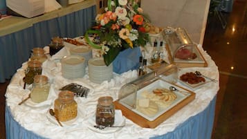 Una mesa de bufé con diversos alimentos, incluyendo frascos de pepinillos, tazones de sopa y una presentación de rebanadas de manzana.