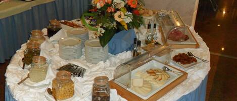 Een buffettafel met diverse gerechten, waaronder potten augurken, kommen soep en een schaal met plakjes appel.