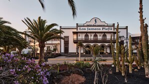 A hotel with a sign reading "Los Jameos Playa" and a palm tree in the foreground. - Seaside Los Jameos (Tías)