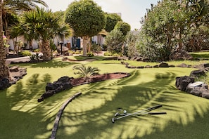 A miniature golf course with a putting green, sand traps, and a few trees.