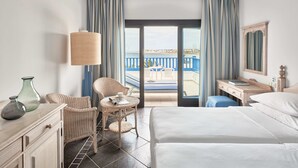 A hotel room with a bed, a desk, a chair, a lamp, and a view of the beach. - Seaside Los Jameos (Tías)