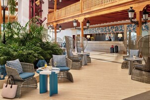 An outdoor seating area with wicker furniture and a reception desk in the background.