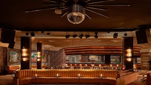 A modern bar area with a curved seating arrangement, overhead lighting, and a disco ball. - Seaside Los Jameos (Tías)