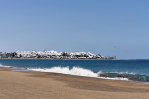 A coastal hotel with a beachfront view, white buildings, and a sandy beach.
