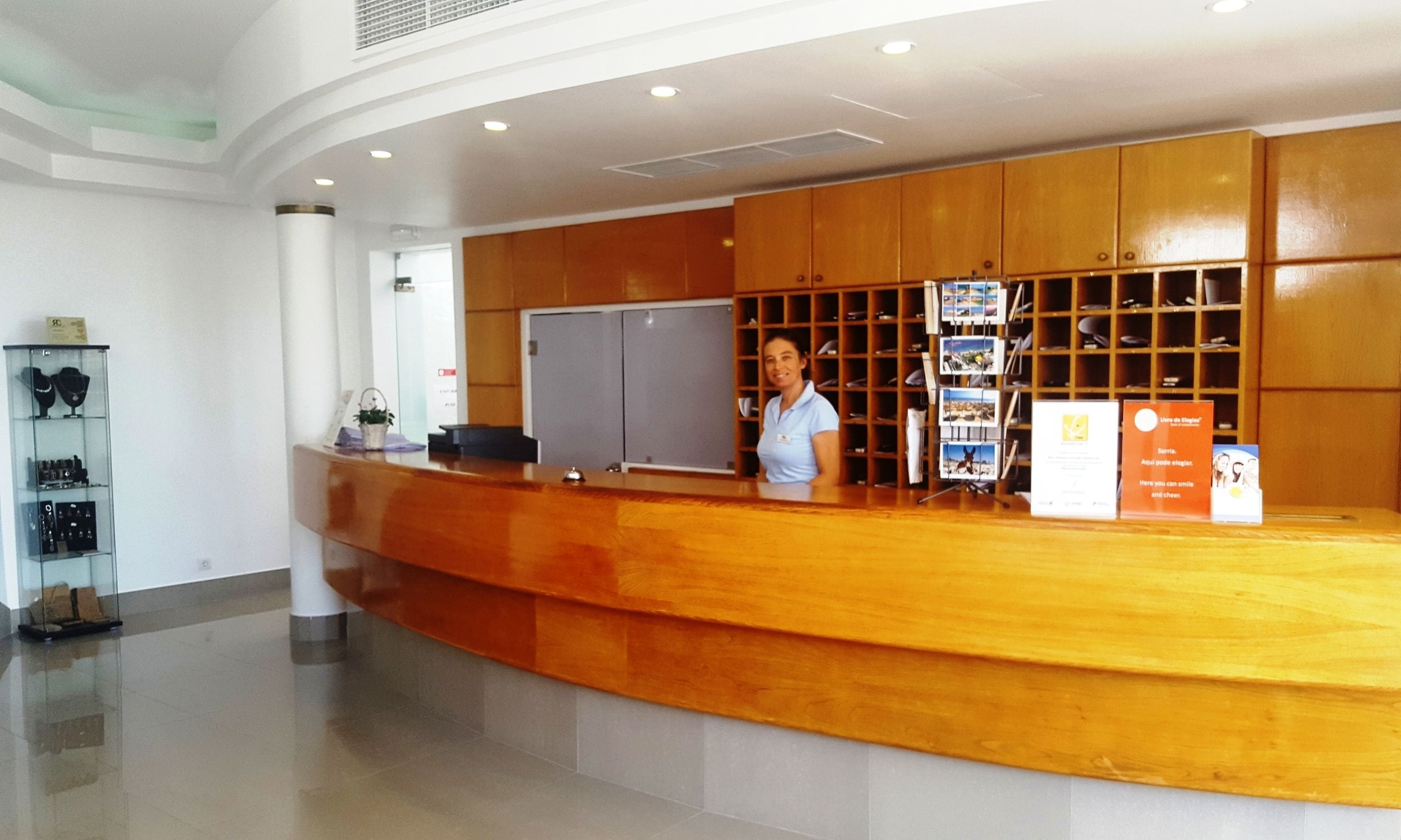 A reception desk with a wooden counter, a receptionist, and a display of framed photos.