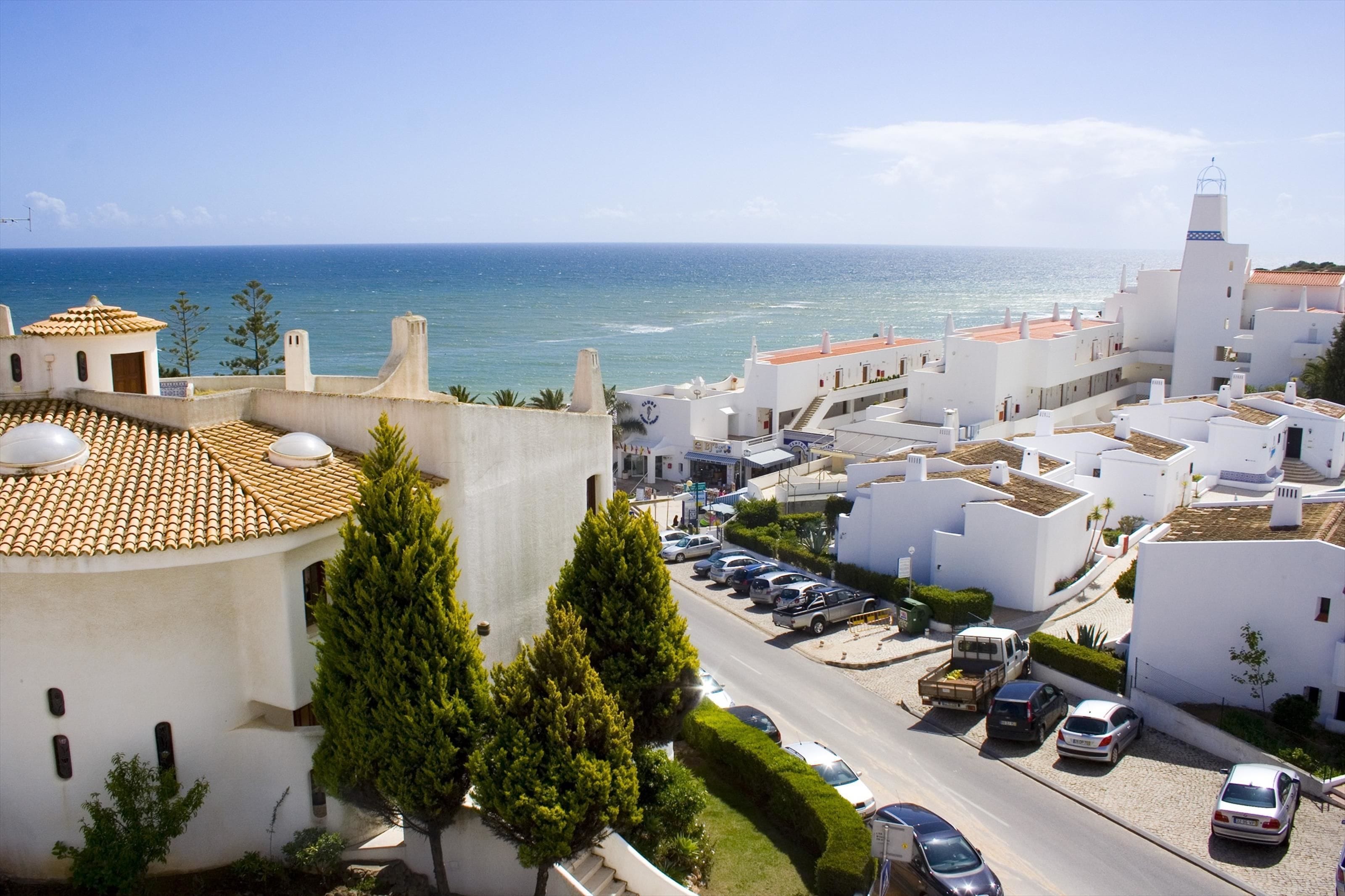 A coastal town with white buildings, a clear blue sky, and the sea in the background.