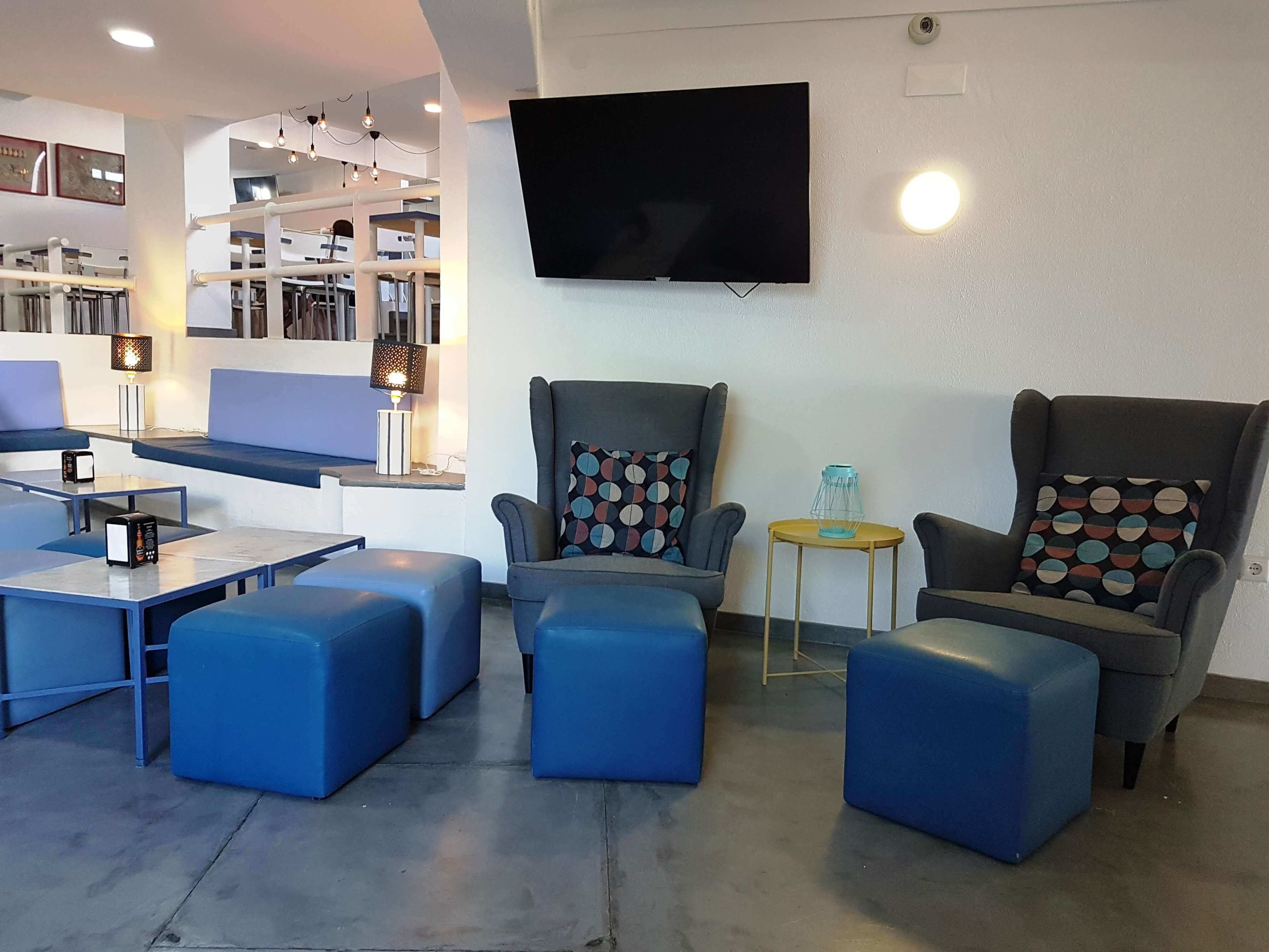 A modern living room with blue seating, a flat-screen TV, and a bookshelf.