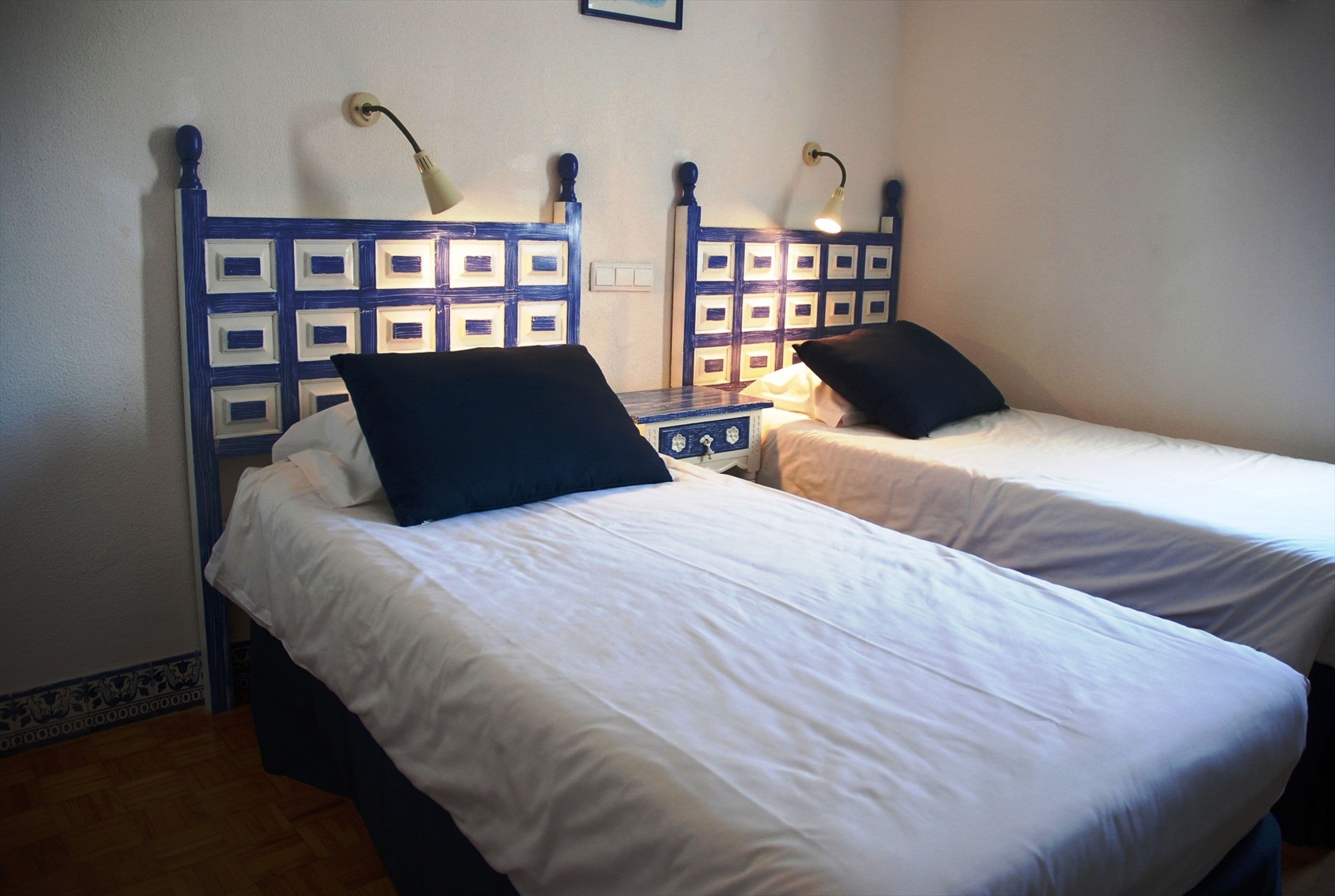 Deux lits simples avec des têtes de lit, du linge de lit blanc et des lampes de chevet.