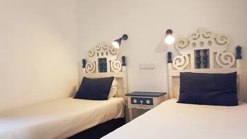 Una habitación con dos camas individuales, cada una con cabecera y mesita de noche.