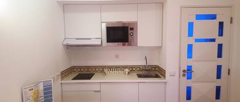 A compact kitchen with a microwave, sink, and a cabinet above the counter.