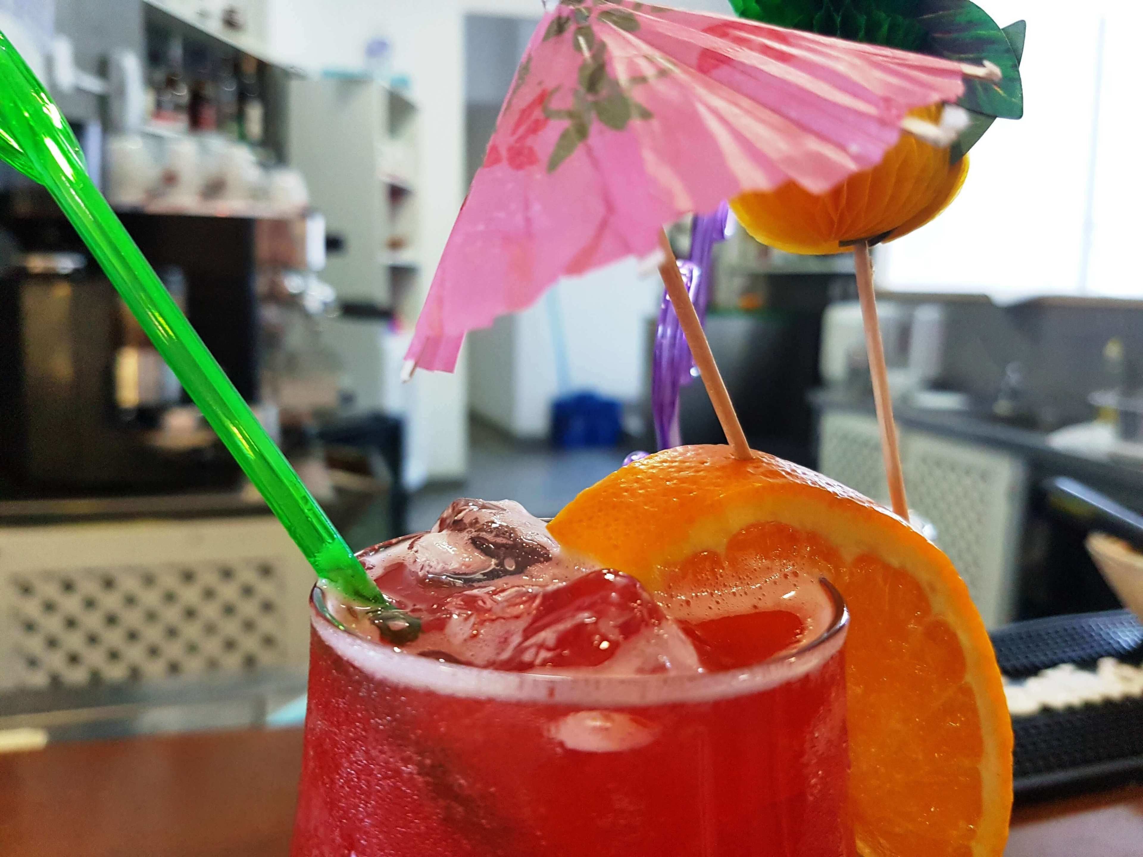 Un cóctel con una rodaja de naranja y un paraguas decorativo en un vaso.