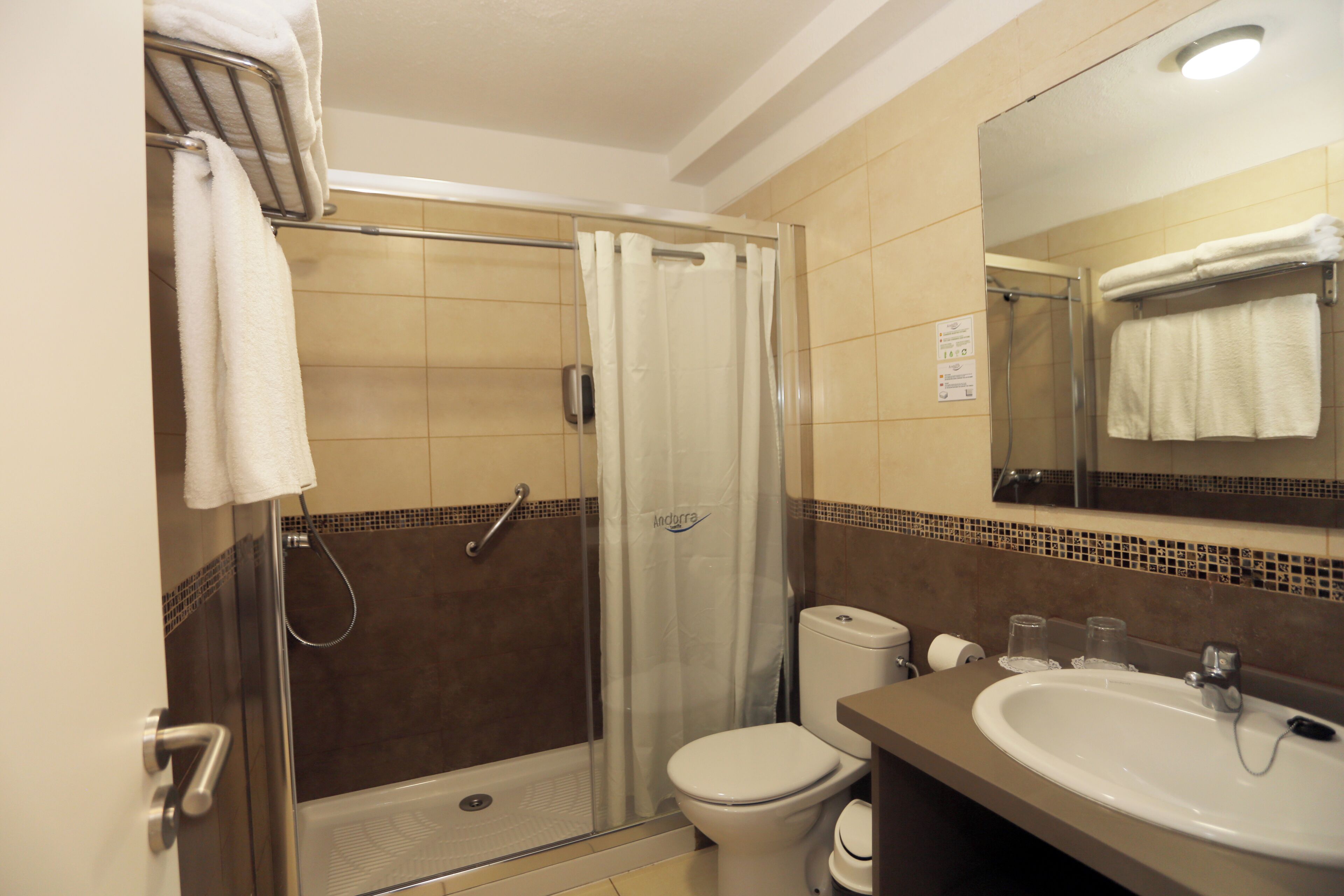 Un baño con ducha, inodoro, lavamanos y espejo.