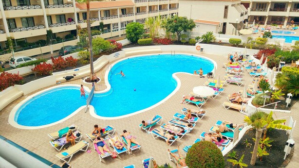 Ein Hotelpoolbereich mit mehreren Pools, Liegestühlen und einer überdachten Sitzgelegenheit.