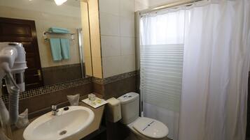 A bathroom with a sink, mirror, towel rack, toilet, and shower curtain.