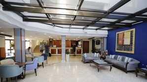 Eine großzügige Lobby mit modernem Design, inklusive blauer Akzentwand, einer großen Couch und einem Couchtisch.