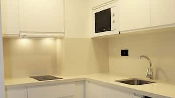 Une cuisine moderne avec des meubles blancs, un four à micro-ondes, un évier et un lave-vaisselle.