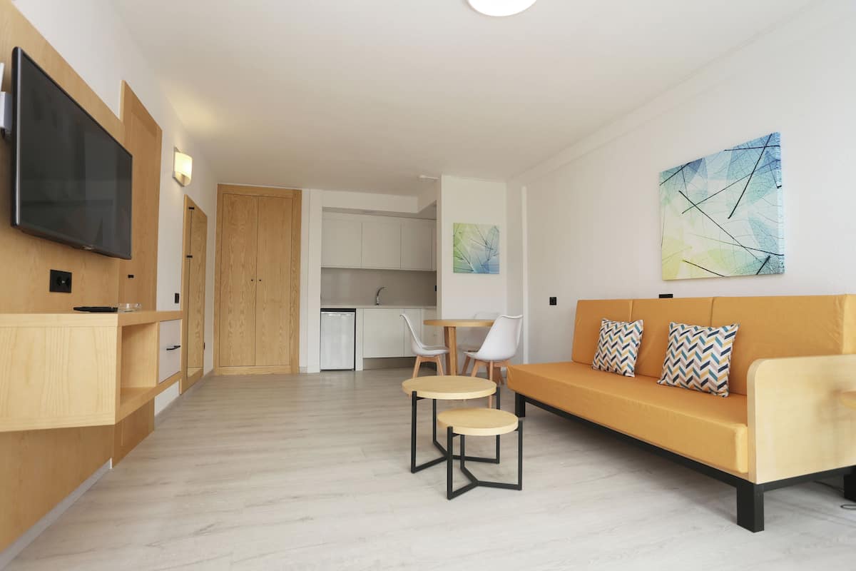 A modern living room with a sofa, two small tables, and a TV mounted on the wall.