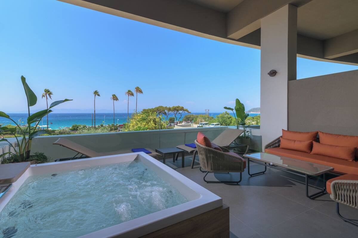 A rooftop terrace with a hot tub, lounge chairs, and a sofa overlooking the ocean.