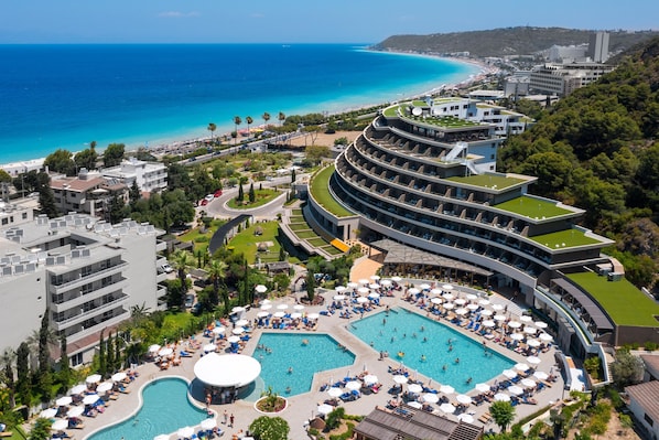 A resort with a large pool area, multiple swimming pools, and a beach view.