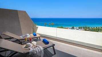 A balcony with two lounge chairs, a table with a hat, a drink, and a towel.