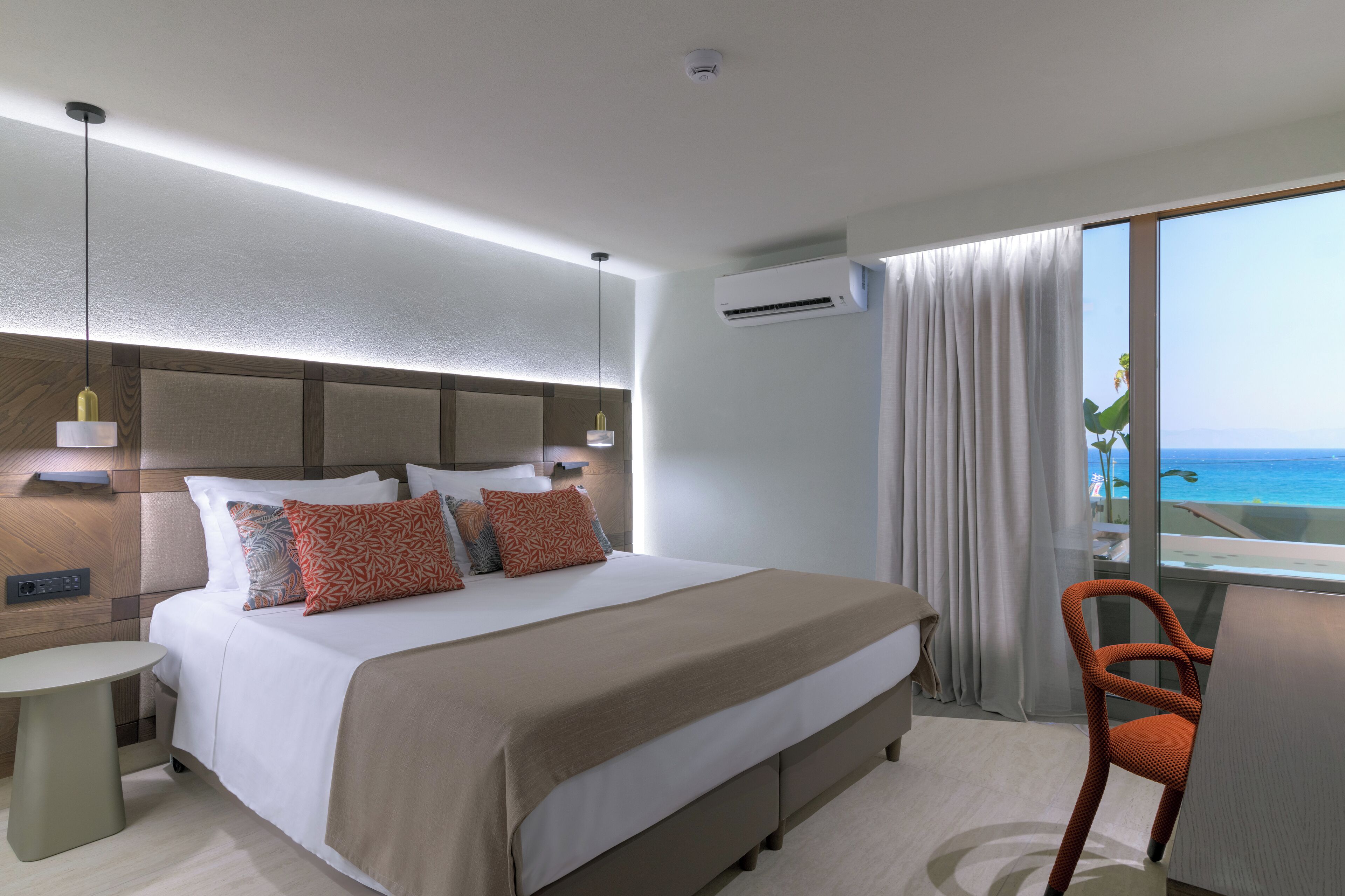 Habitación de hotel moderna con una cama grande, un escritorio y vistas al océano.