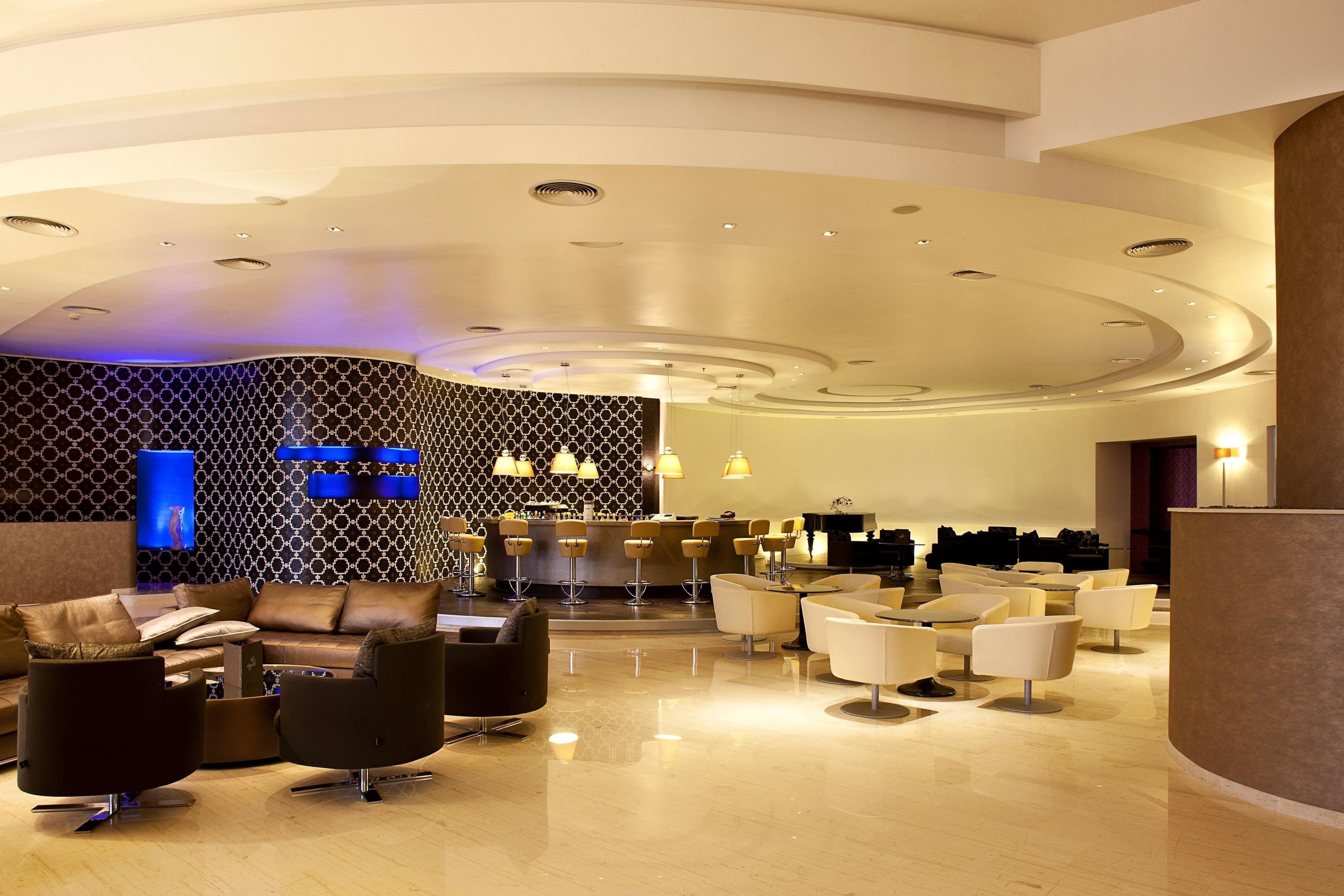 En rymlig entréhall med en receptionsdisk, flera sittgrupper och en modern takdesign.