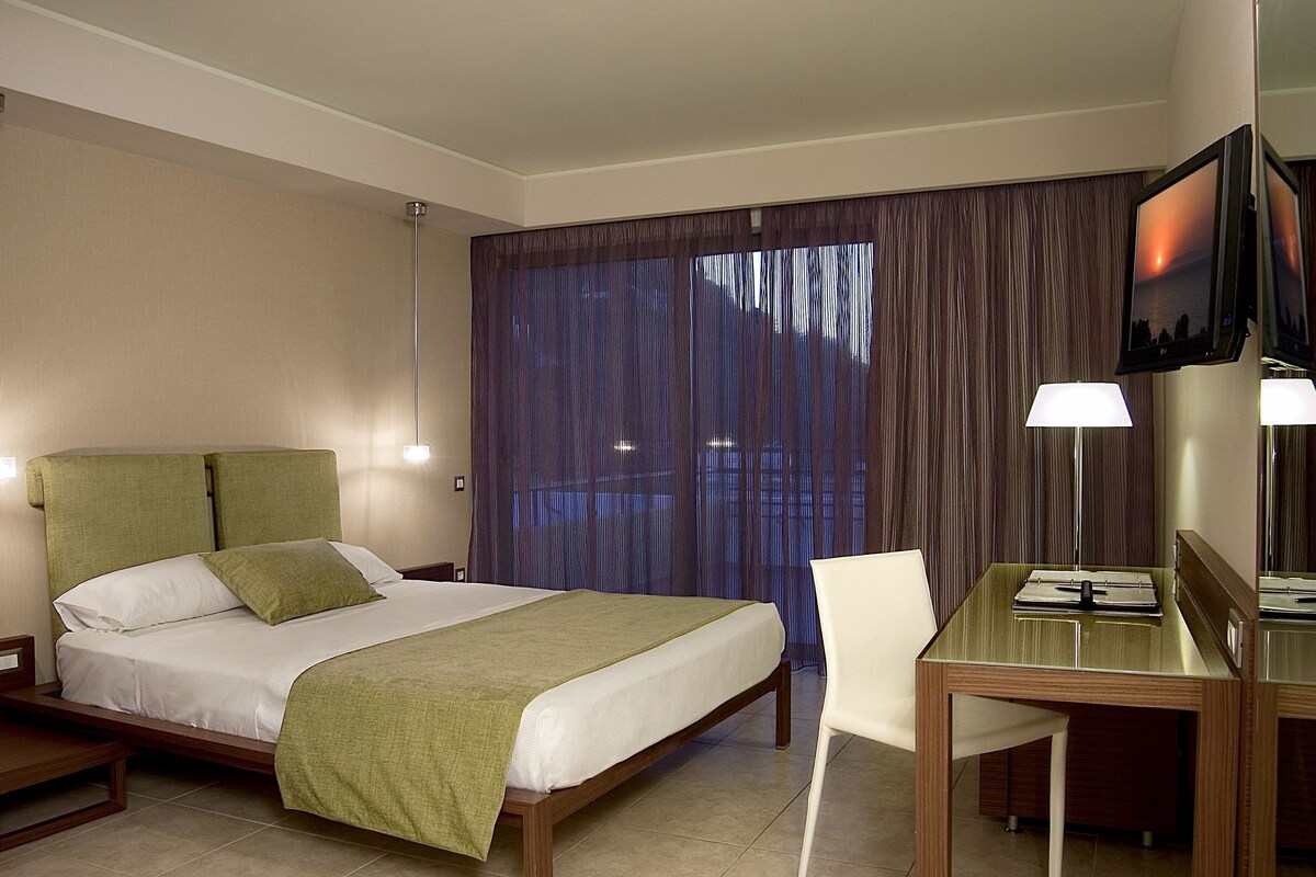Een hotelkamer met een bed, een bureau, een stoel en een televisie.